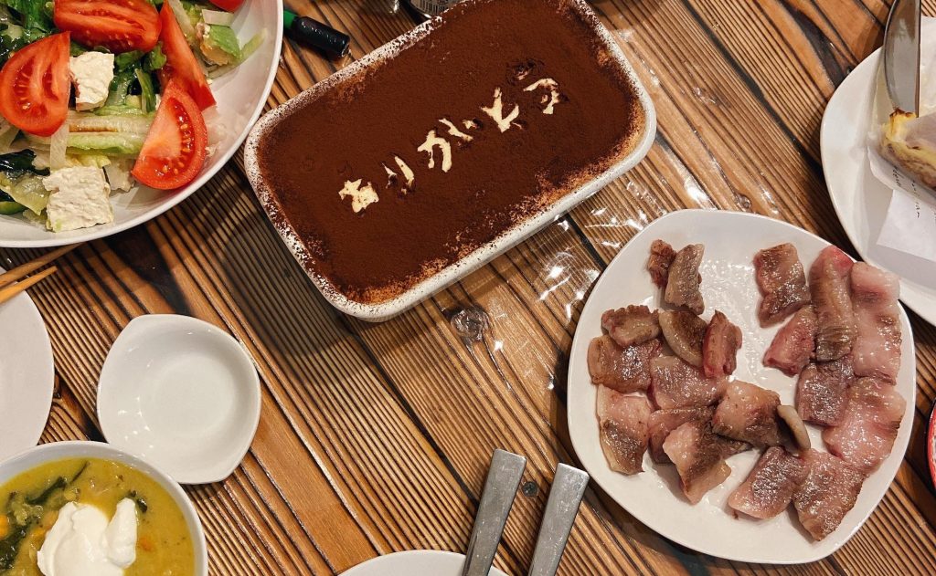杉のテーブルに料理の皿が並んでいる
