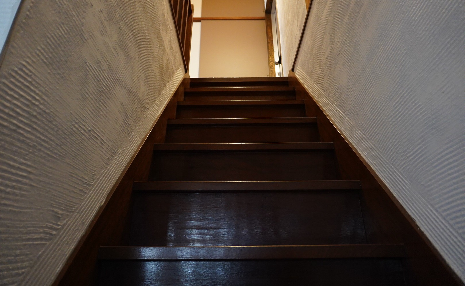 下から見上げた木の階段と白い漆喰の壁